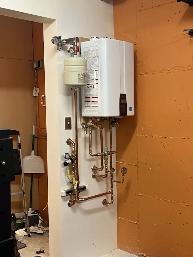 Plumbing technician inspecting water heater connections in Attica